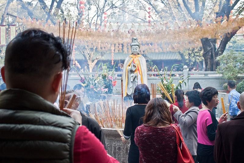 Gente rezando con inciensos ante la estatua de una diosa en el templo de Haitang.